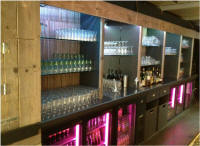 Bar achterwand van steigerhout met gekleurde verlichting.